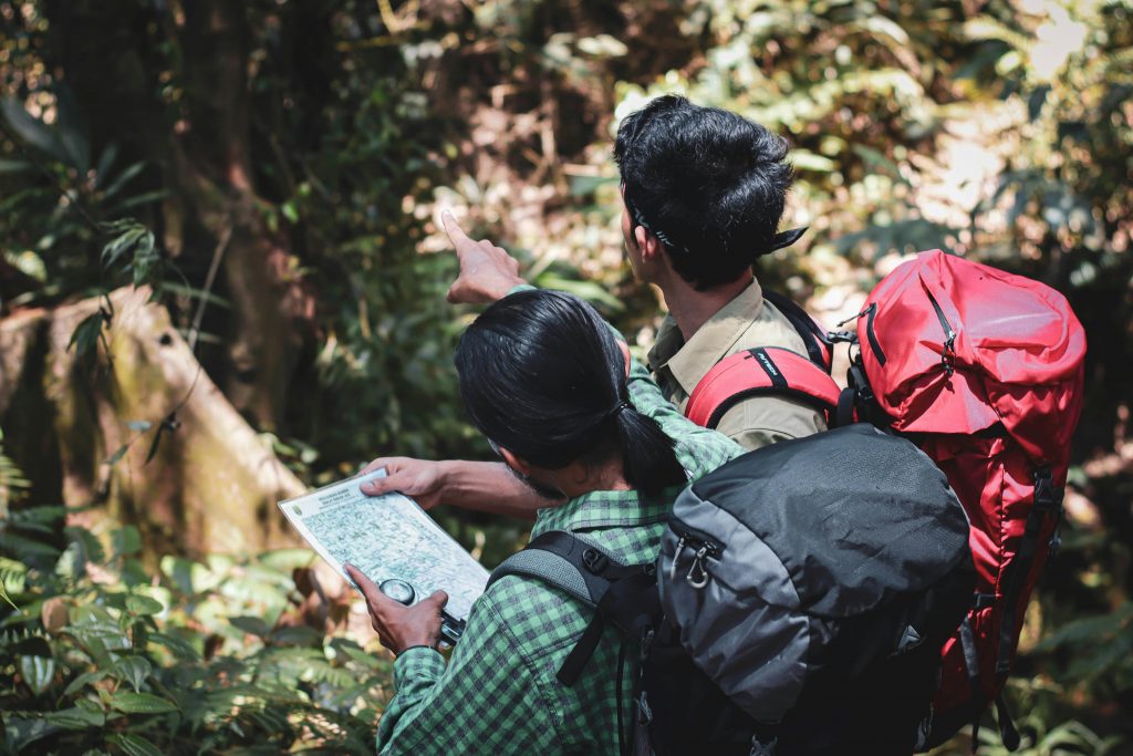 Photo of two people looking at a map in a rainforest